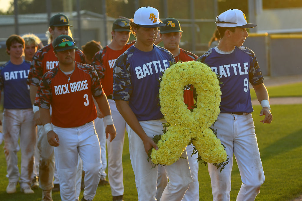 Players from both Rock Bridge and Battle baseball lay a wreath